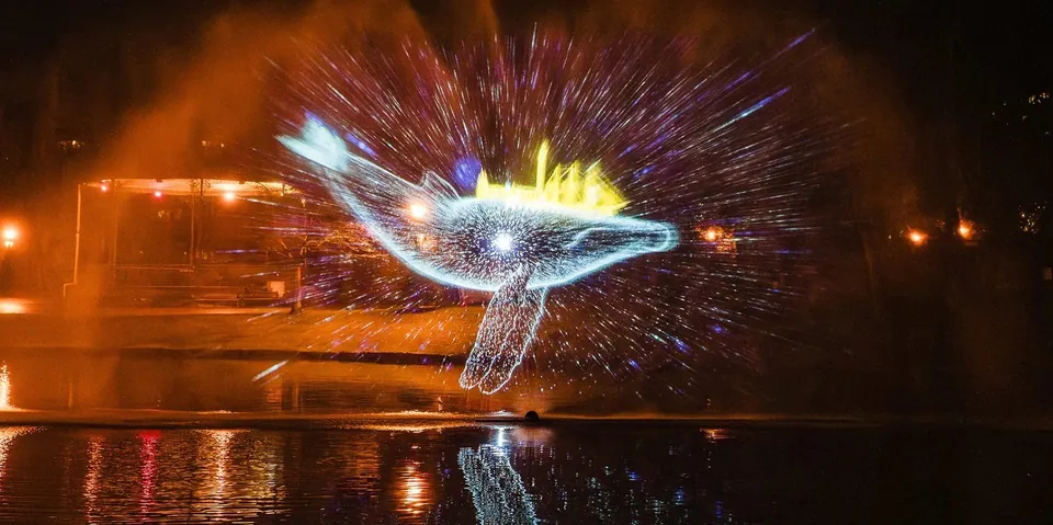 Glowing whale projected onto a water screen at night during Lichtgolf